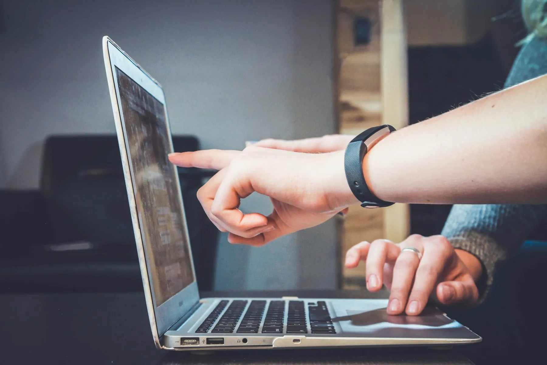 Zwei Personen zeigen auf einen Laptop-Bildschirm und besprechen Änderungen an ihrer Website